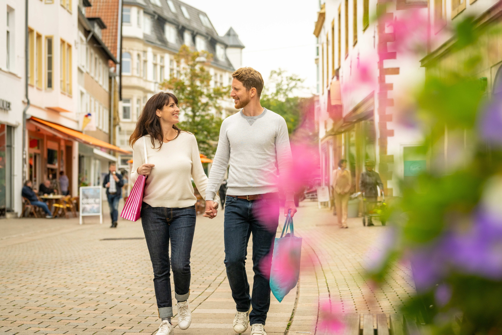 ein Mann und eine Frau schlendern durch die Obernstraße in Bielefeld und tragen Einkaufstüten