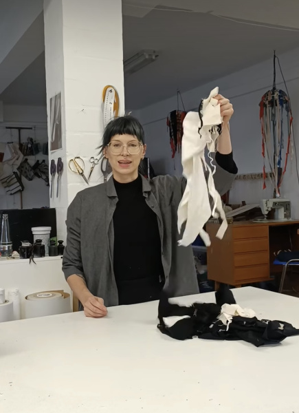 die Designerin Julia Schürmann in ihrer Werkstatt hält Stoffreste hoch und macht daraus Schmuck
