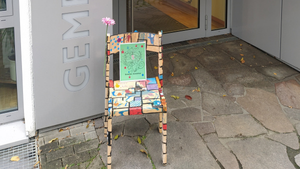 ein gestalteter Stuhl mit einer Nummer steht vor dem Eingang vom Gemeindehaus