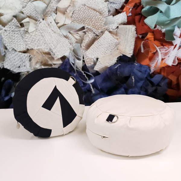 Zwei Sitzkissen in Schwarz-Weiß auf weißem Untergrund mit bunten Stoffresten im Hintergrund