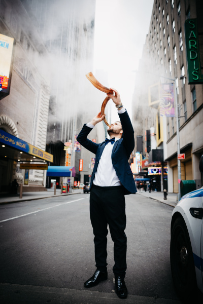 Bar Zemach  bläst auf einer Straße in ein gebogenes Horn (Schofar).