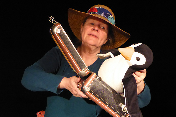 Eine Frau mit einem Pinguin, der im Koffer sitzt