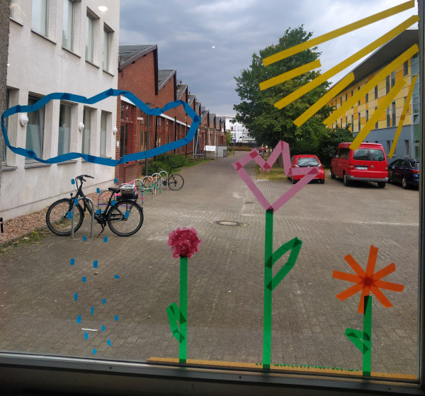 auf einer Fensterscheibe sind Blumen, Wolken, Regentropfen mit Kreppbändern aufgeklebt