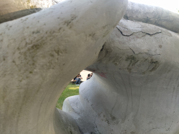 durch die Aushöhlung einer Skulptur zwei Menschen beim Schreiben fotografiert