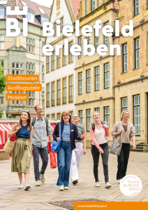 Gruppe von Touristen auf einem Platz in einer historischen Altstadt mit farbigen Gebäuden.